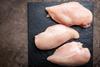 Raw chicken breasts on a board