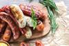 Cooked sausages on a wooden serving board, garnished with herbs.