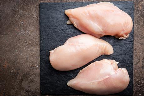 Raw chicken breasts on a board