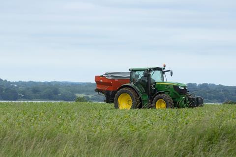Tractor spreading fertiliser in maizecorn field
